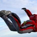 Skydiver in a red suit holding a stable arched freefall position