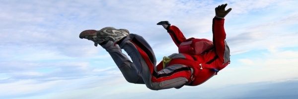 Skydiver in a red suit holding a stable arched freefall position